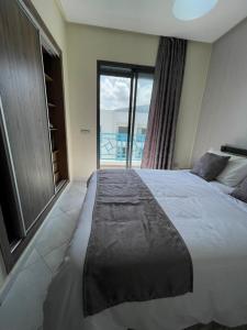 um quarto com uma cama grande e uma janela grande em APPART SMIR PARK em Tétouan