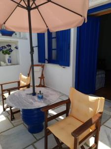 una mesa y sillas con una sombrilla en el patio en Ioanna's en Pánormos