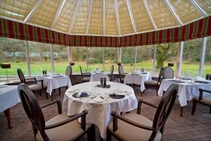 a restaurant with white tables and chairs and windows at Isle of Eriska Hotel Spa & Island in Benderloch