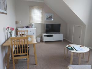 a living room with a table and a television at The Gem in Winchelsea