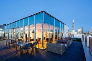 uma varanda de um edifício com mesas e cadeiras em Chic Studios and Apartments at Chapter South Bank in London em Londres
