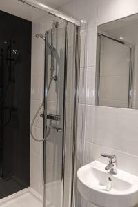 a bathroom with a shower and a sink and a mirror at For Students Only Collegiate Eclipse Cardiff in Cardiff +16 photos