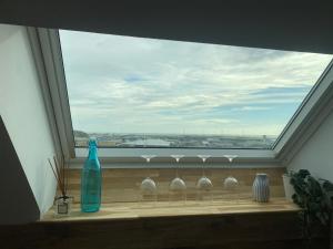 ein Fenster mit vier Weingläsern und einer blauen Flasche in der Unterkunft Studio Vue Mer in Boulogne-sur-Mer