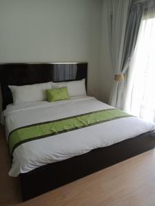 a large bed with a green pillow on top of it at Zotel in Chiang Mai