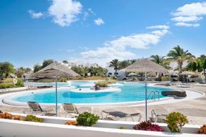 a pool at a resort with chairs and umbrellas at Calimar Los Molinos in Costa Teguise