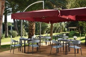 a patio area with tables, chairs and umbrellas at Park Hotel Marinetta in Marina di Bibbona