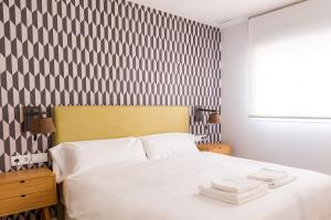 um quarto com uma cama branca com riscas pretas e brancas em TreeTriana em Sevilha