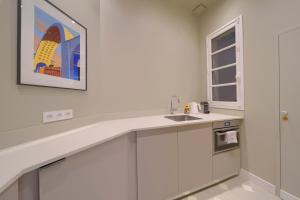 eine Küche mit einem Waschbecken und einem Gemälde an der Wand in der Unterkunft Le Nuage - Studio design à Triangle d'Or in Bordeaux