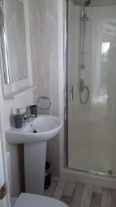 a white bathroom with a sink and a shower at KINGDOM HOLIDAY PARK - Parrot in Millom