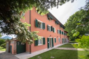 an orange building with green shutters and a yard at Relais Villa Isabel in Pietrasanta