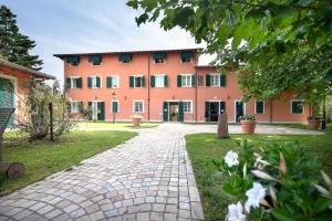 a large pink building with a brick walkway at Relais Villa Isabel in Pietrasanta