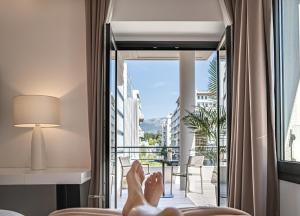 a person laying in a hotel room with their feet on the window at The Marblous Athens in Athens