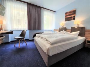 a hotel room with a bed, chair, desk and a television at Melarose Feng Shui Hotel in Berlin