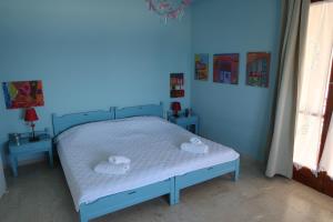 a blue bedroom with a bed with two towels at Akrogiali Beach Apartments in Akrogiali