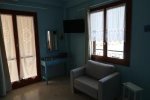 a blue room with a chair and a window at Akrogiali Beach Apartments in Akrogiali