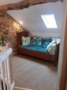 a couch in a room with a stone wall at Chambre pranayama in Montcléra