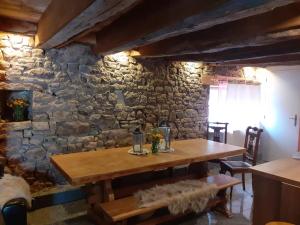 a wooden table in a room with a stone wall at Chambre pranayama in Montcléra