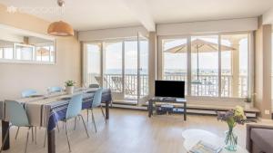 een eetkamer met een tafel en stoelen en een televisie bij Epsom - Appartement en front de mer Arcachon in Arcachon