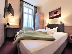 a hotel room with a bed, desk, and nightstand at Melarose Feng Shui Hotel in Berlin