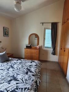 Schlafzimmer mit einem Bett, einer Kommode und einem Spiegel in der Unterkunft Melanta Villa in Pissouri