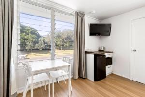 a room with a table and chairs and a window at Surf Beach Motel Coffs in Coffs Harbour