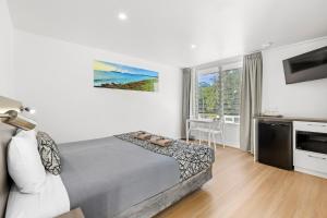 a bedroom with a bed and a large window at Surf Beach Motel Coffs in Coffs Harbour