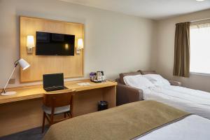 a hotel room with a bed and a desk with a laptop at Boat & Horses Inn in Oldham