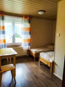 een kamer met 2 bedden, een tafel en een raam bij Jeleni Skok in Cisna