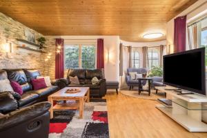 a living room with leather furniture and a flat screen tv at Villa Kanisblick in Bizau