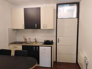 a kitchen with white cabinets and a sink and a table at Rogla Apartma Gaber54 in Zreče
