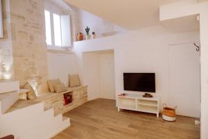 a white living room with a television and stairs at INDE Á LA TERRE, GUEST HOUSE Locazione Turistica in Molfetta