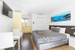 a bedroom with a bed and a desk at Surf Beach Motel Coffs in Coffs Harbour