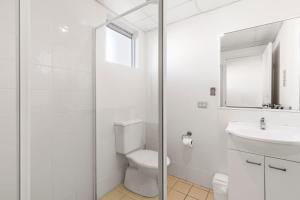 a white bathroom with a toilet and a sink at Surf Beach Motel Coffs in Coffs Harbour