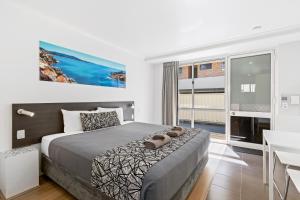 a bedroom with a bed and a table and a desk at Surf Beach Motel Coffs in Coffs Harbour