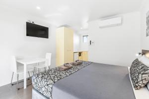 a bedroom with a bed and a table and a desk at Surf Beach Motel Coffs in Coffs Harbour