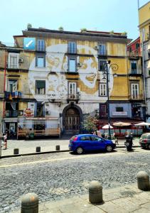 una macchina blu parcheggiata di fronte a un edificio con un murale di ANDREA'S HOUSE a Napoli
