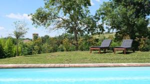 two chairs sitting in the grass next to a swimming pool at DEMEURE LE COLOMBIER in Sainte-Croix