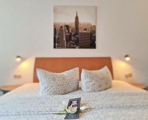a bed with two pillows and a picture of a city at Hotel Marktbrauerei in Bad Lobenstein