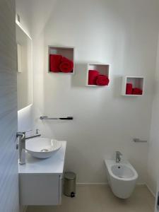 Baño blanco con rosas rojas en la pared en Gassa d amante Affittacamere, en Stintino