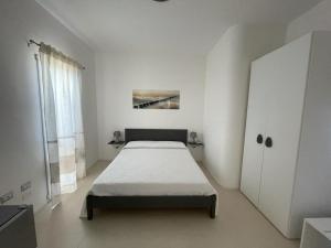a white bedroom with a bed and a cabinet at Gassa d amante Affittacamere in Stintino