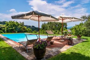 una piscina con 2 sombrillas y sillas y una mesa en Appartamento Giulio, en Villamagna