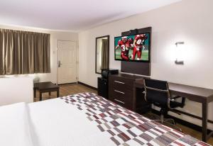 a hotel room with a bed and a flat screen tv at Red Roof Inn & Suites Commerce - Athens in Commerce