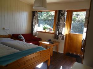 a bedroom with a bed and a couch and windows at Kvamsdal Pensjonat 2 in Eidfjord