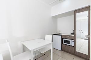 a kitchen with a white table and a microwave at Surf Beach Motel Coffs in Coffs Harbour
