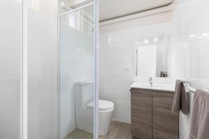 a bathroom with a toilet and a glass shower at Surf Beach Motel Coffs in Coffs Harbour