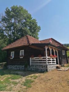 una cabaña de madera con porche y flores. en Etno selo Raković, en Ivanjica