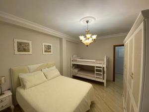 a bedroom with a white bed and a chandelier at Perla Del Sol 1 l in Torremolinos