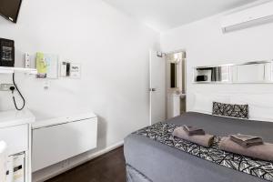 a small white room with a bed and a kitchen at Surf Beach Motel Coffs in Coffs Harbour