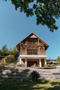 a large wooden house with a large balcony at Hej na Mazury Apartamenty in Ruciane-Nida