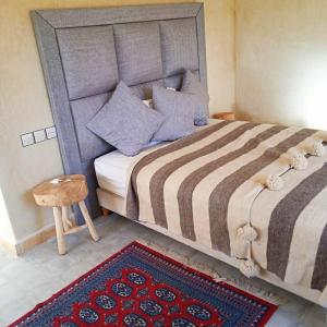 a bedroom with a large bed with a table and a rug at Le petit Jardin in Demnat